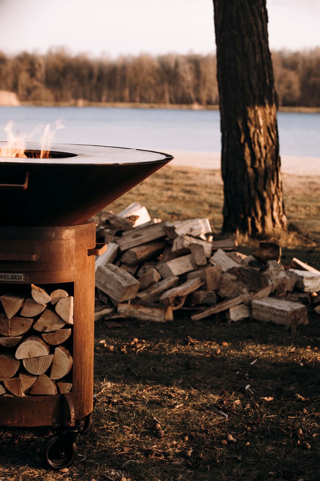 OFYR Plancha met stapel ovengedroogd beukenhout aan een meer
