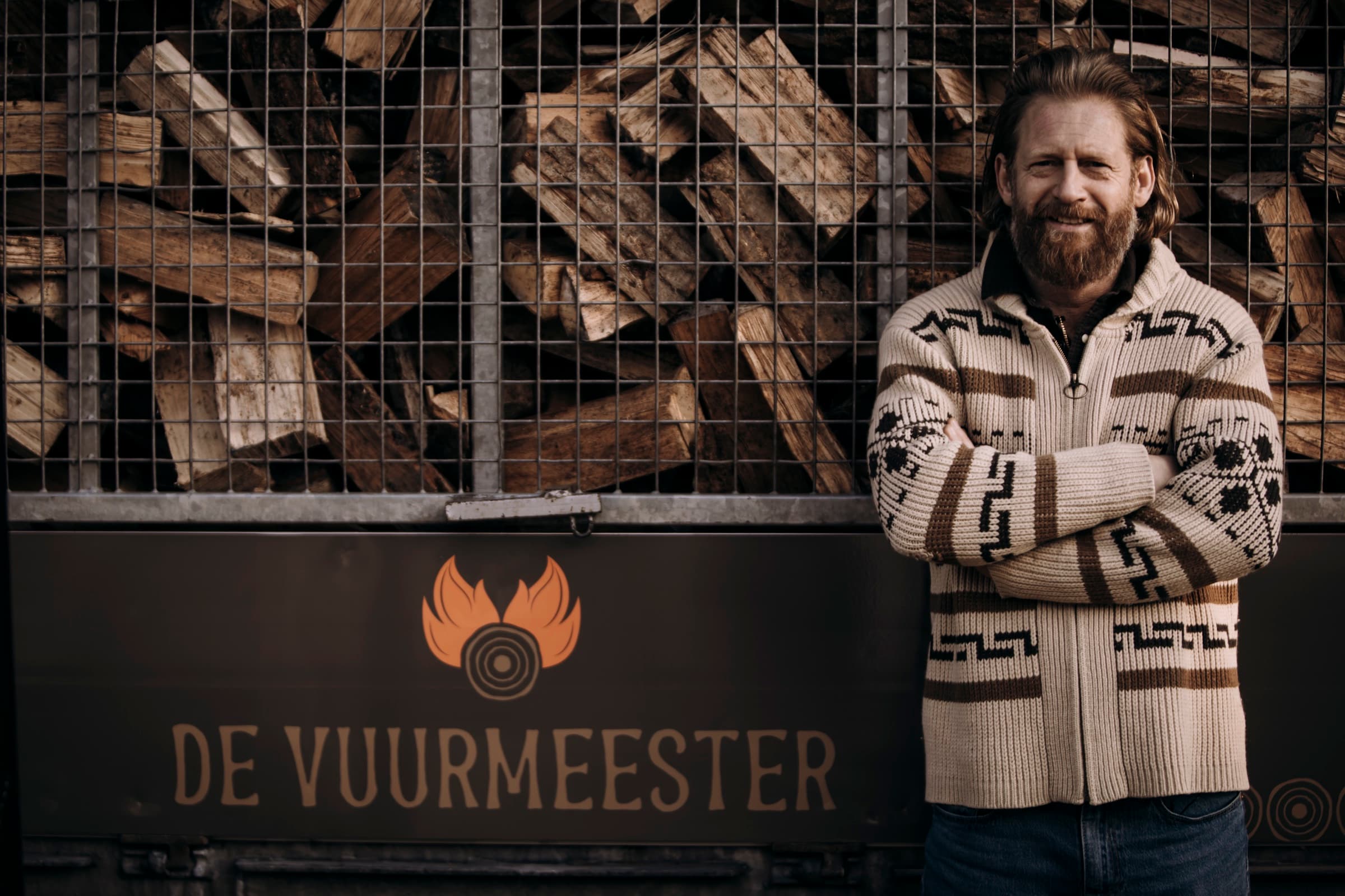 De Vuurmeester bij een voorraad haardhout